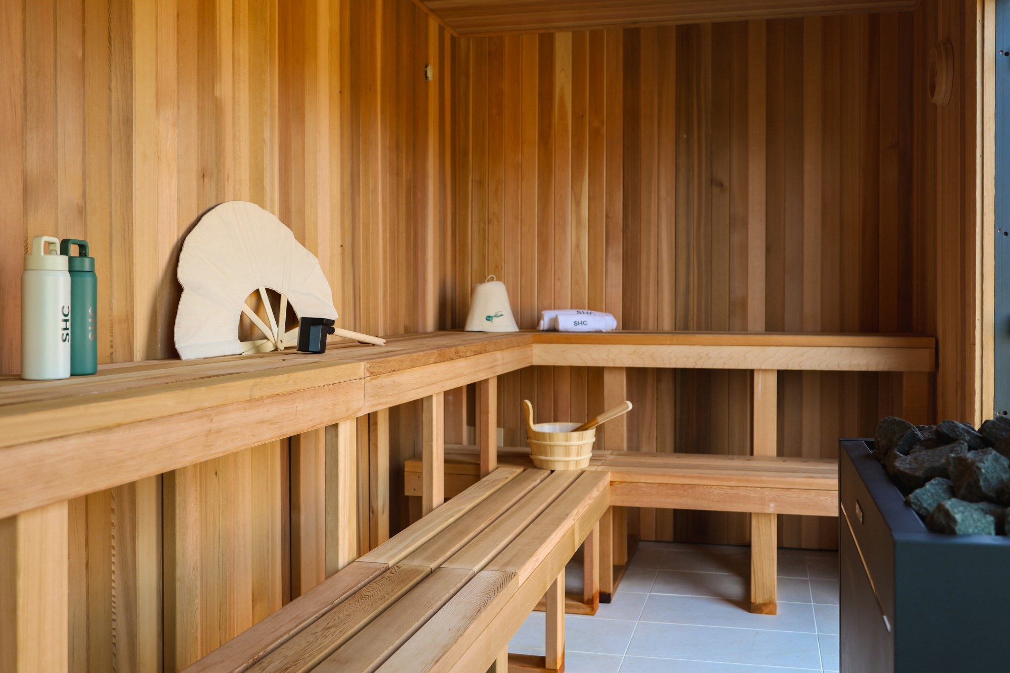 Cedar sauna interior with benches, sauna stones and SHC water bottles